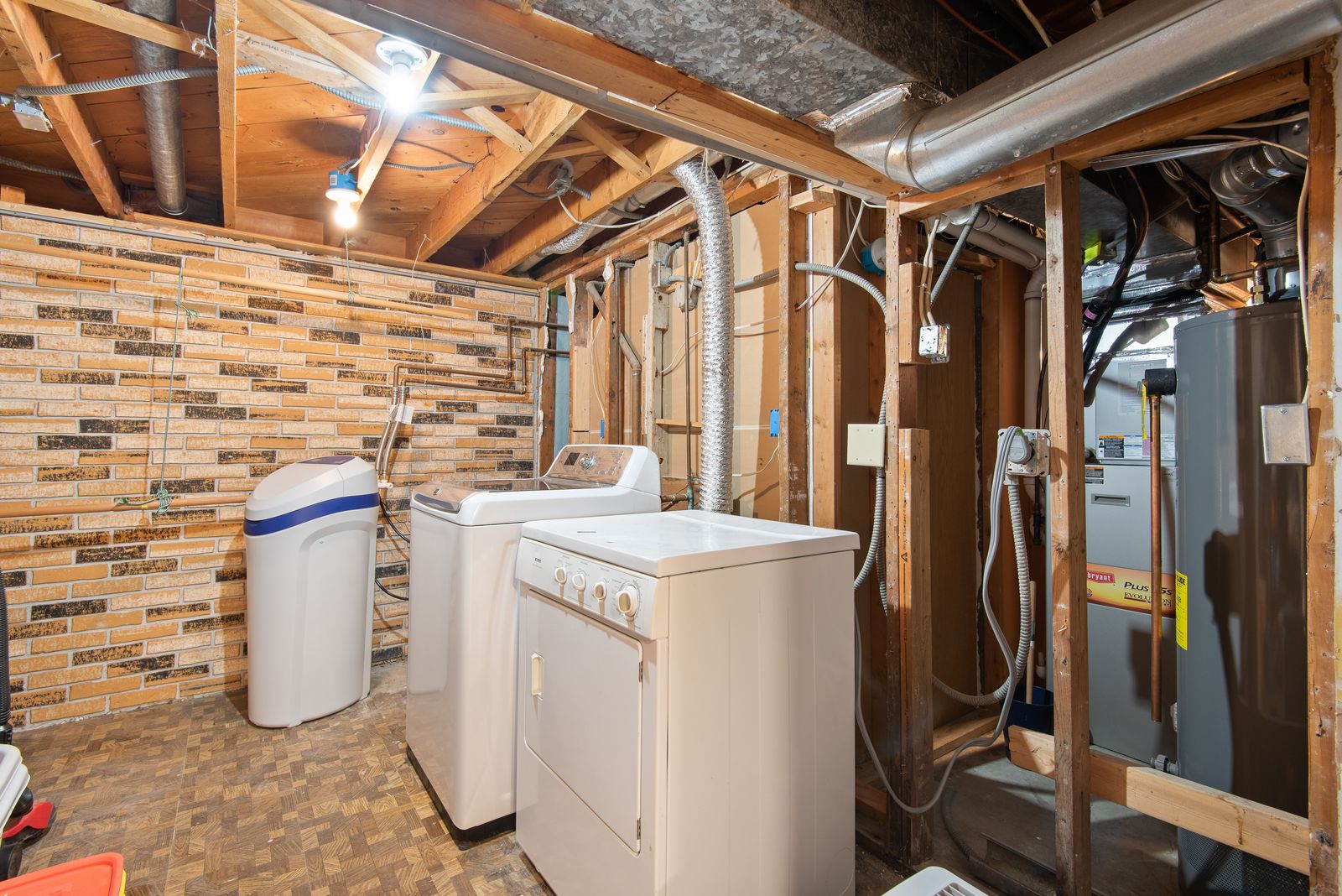 Unfinished basement with a water heater, laundry, and exposed utility lines