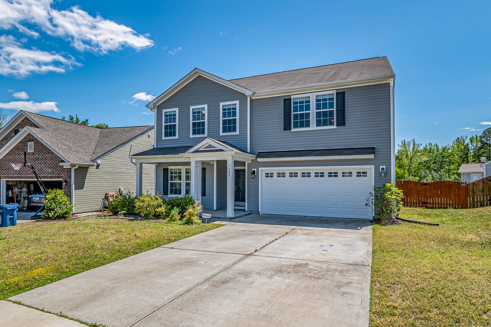 Two-story home with a light gray concrete driveway leading to the garage